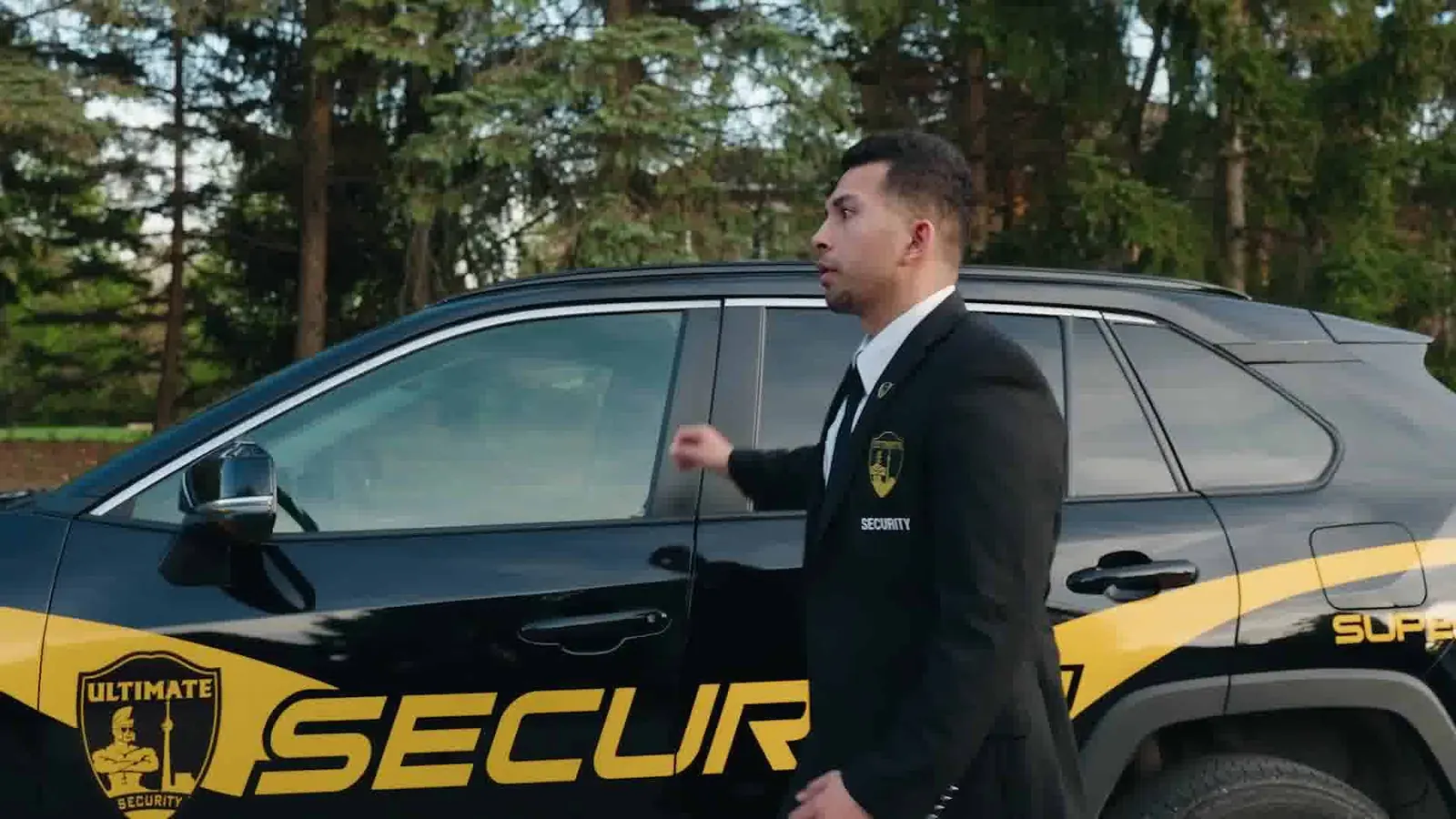 Officer standing beside a marked Ultimate Security patrol vehicle