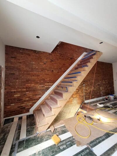 In-progress staircase renovation featuring exposed brick walls