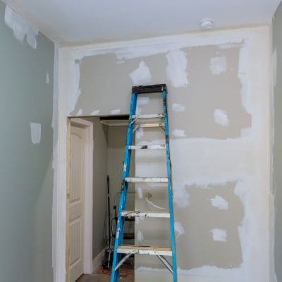 Room with drywall repairs and preparation for painting.