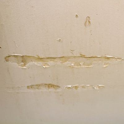 Close-up of damaged drywall showing peeling and wear