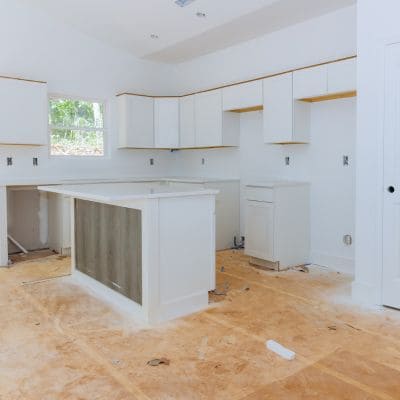 Kitchen renovation in progress with white cabinets being installed.