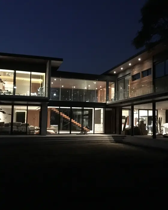 Casa con ventanales de piso a techo iluminada de noche