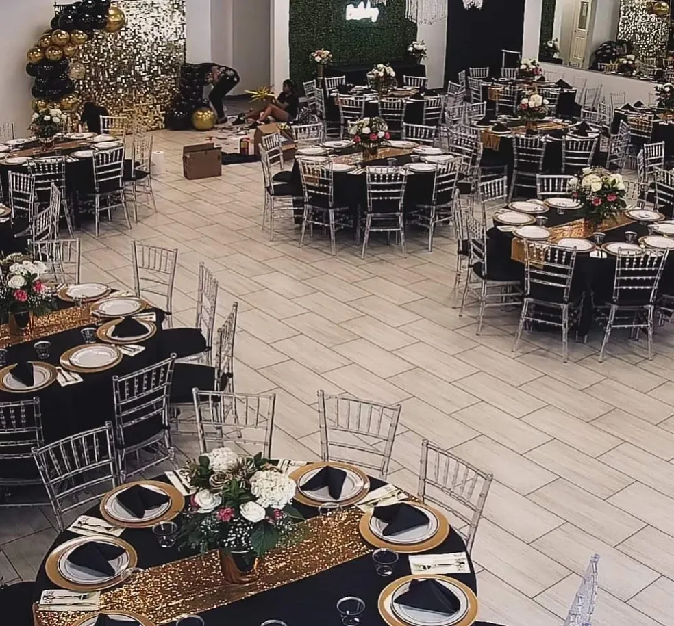 Black and gold balloon garland over a gold sequin backdrop with a greenery wall