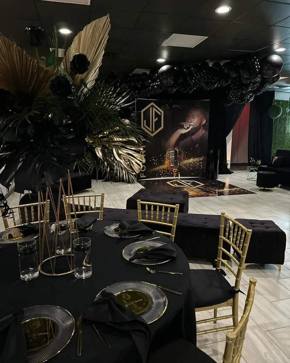 A dark greenery backdrop wall with lounge seating and gold accents