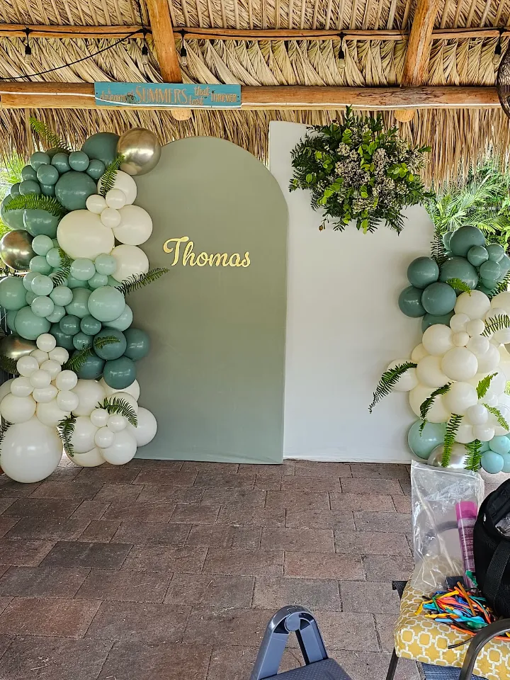 A sage green and white organic garland framing an arched backdrop with greenery