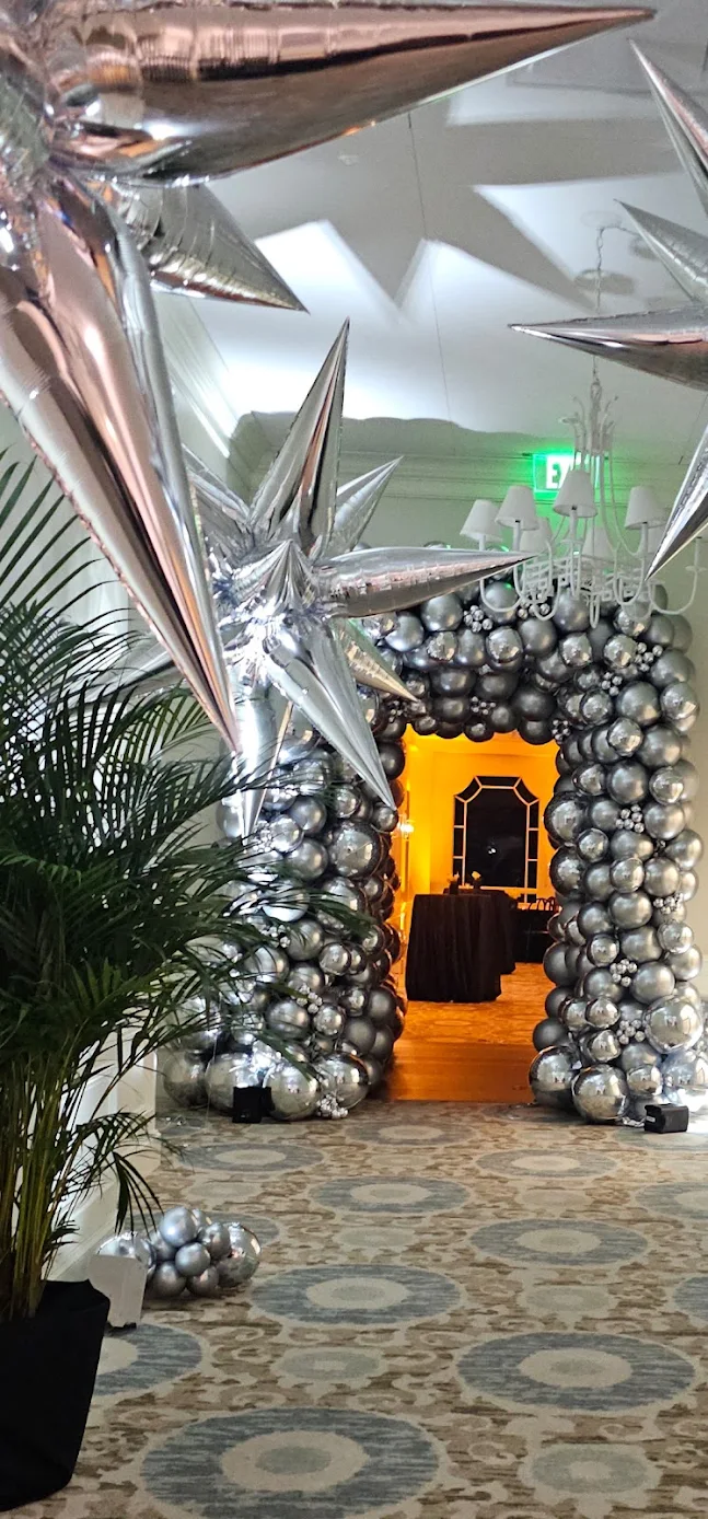 A silver and chrome balloon arch with starburst accents framing an event entrance