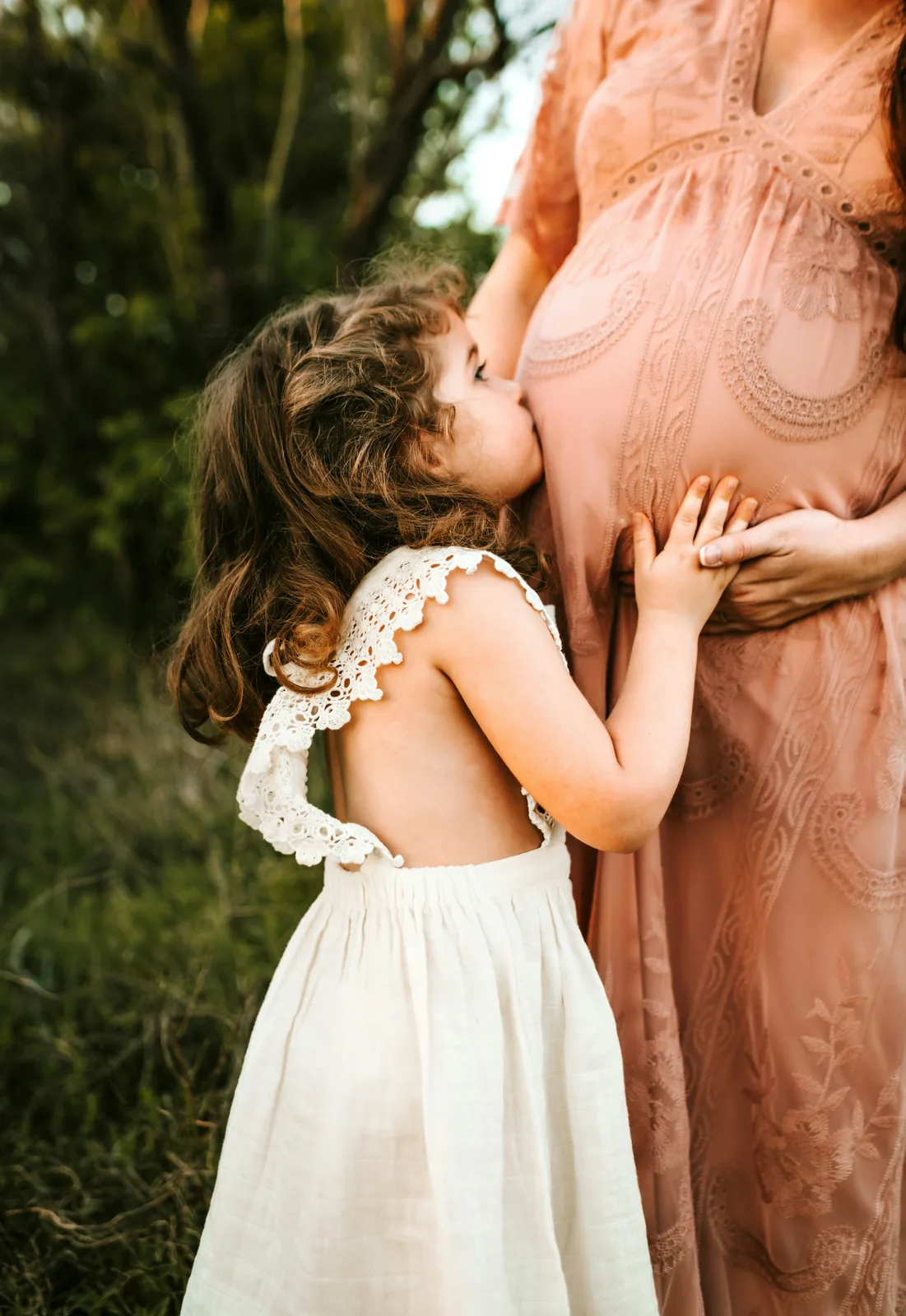 Young girl hugging her pregnant mother's belly