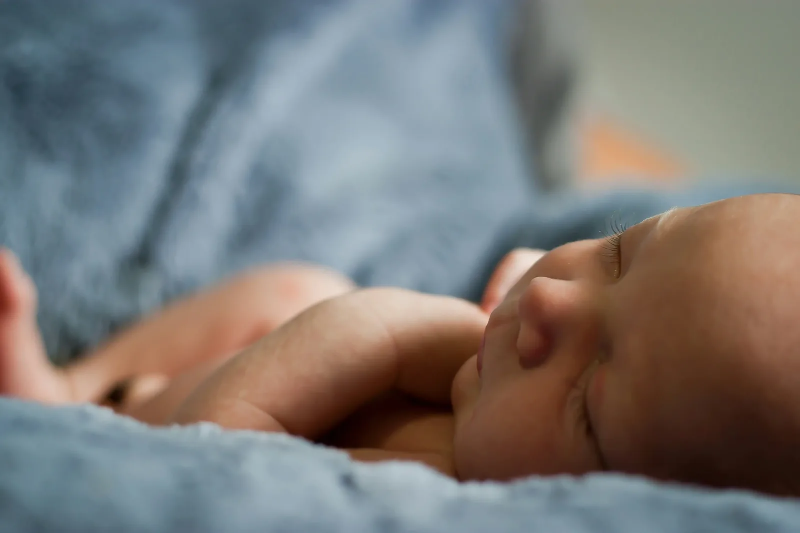 Newborn baby sleeping peacefully on a soft blue blanket