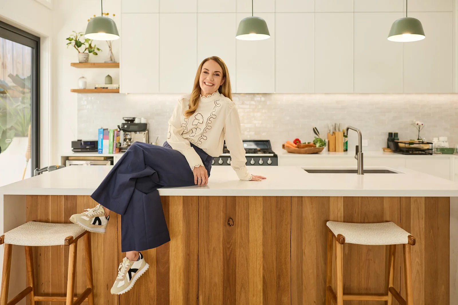 Sonia Savage, functional nutritionist, sitting on her kitchen bench