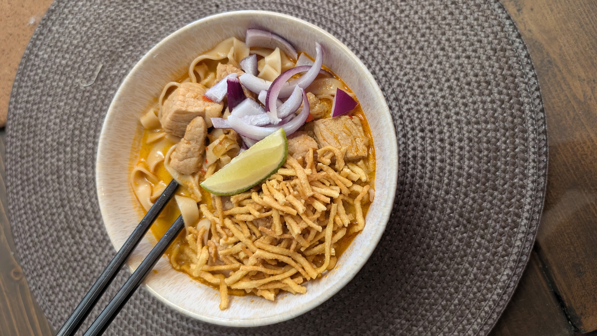 A finished bowl of Khao Soi 1940 with chicken, topped with crispy noodles, shallots, and coriander