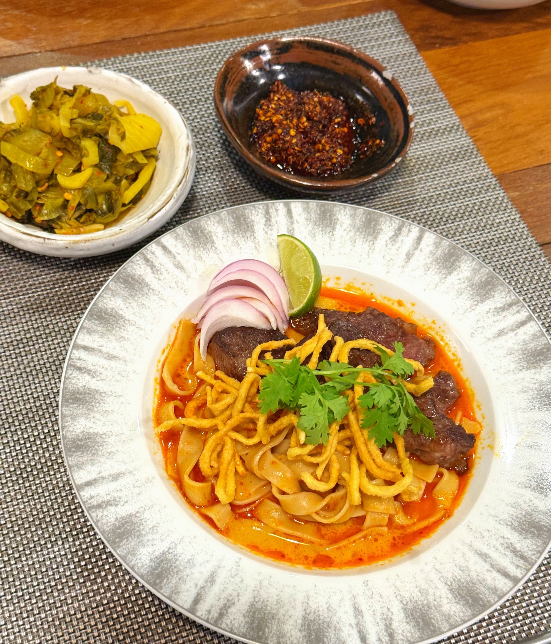 A finished bowl of Khao Soi 1940 with beef, topped with crispy noodles, shallots, and coriander
