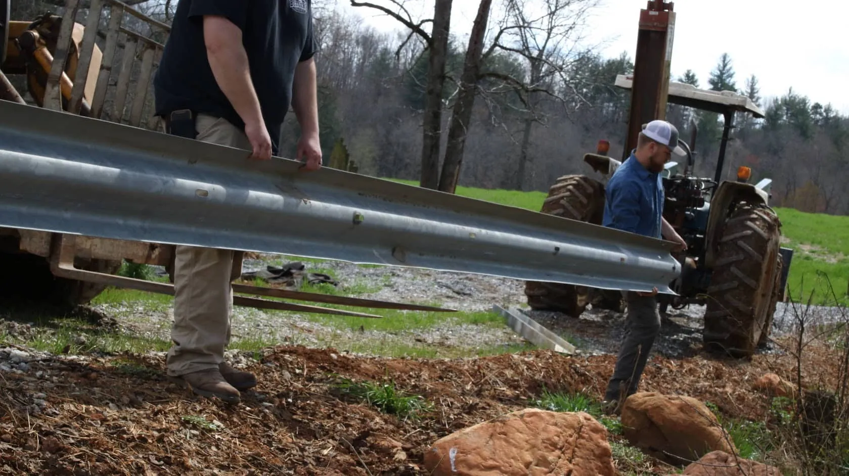 Crew installing guardrail fencing with a tractor