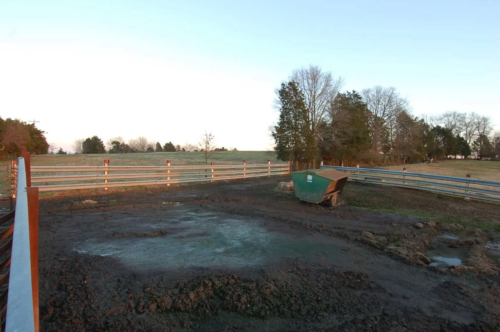 Guardrail fence around a muddy cattle pen