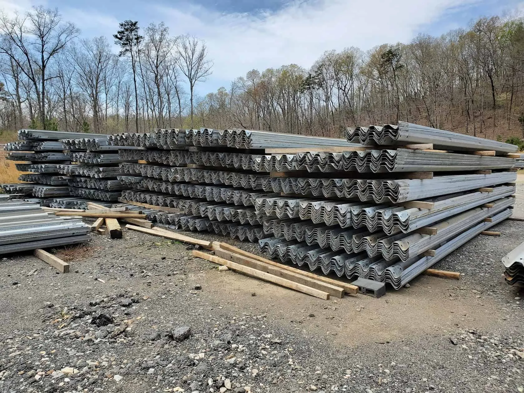 Stacks of used W-beam guardrail panels in a yard