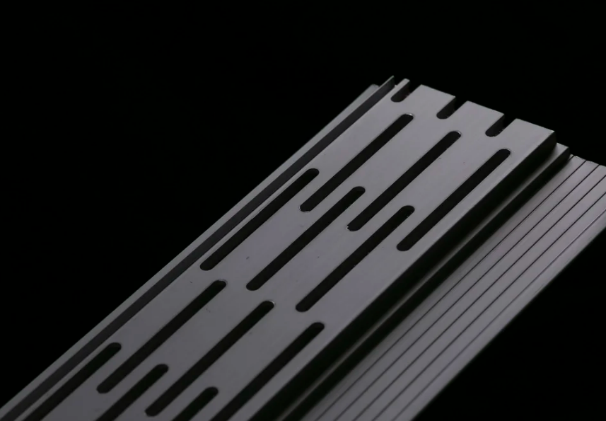Close-up of a gutter component with parallel slots against a black background