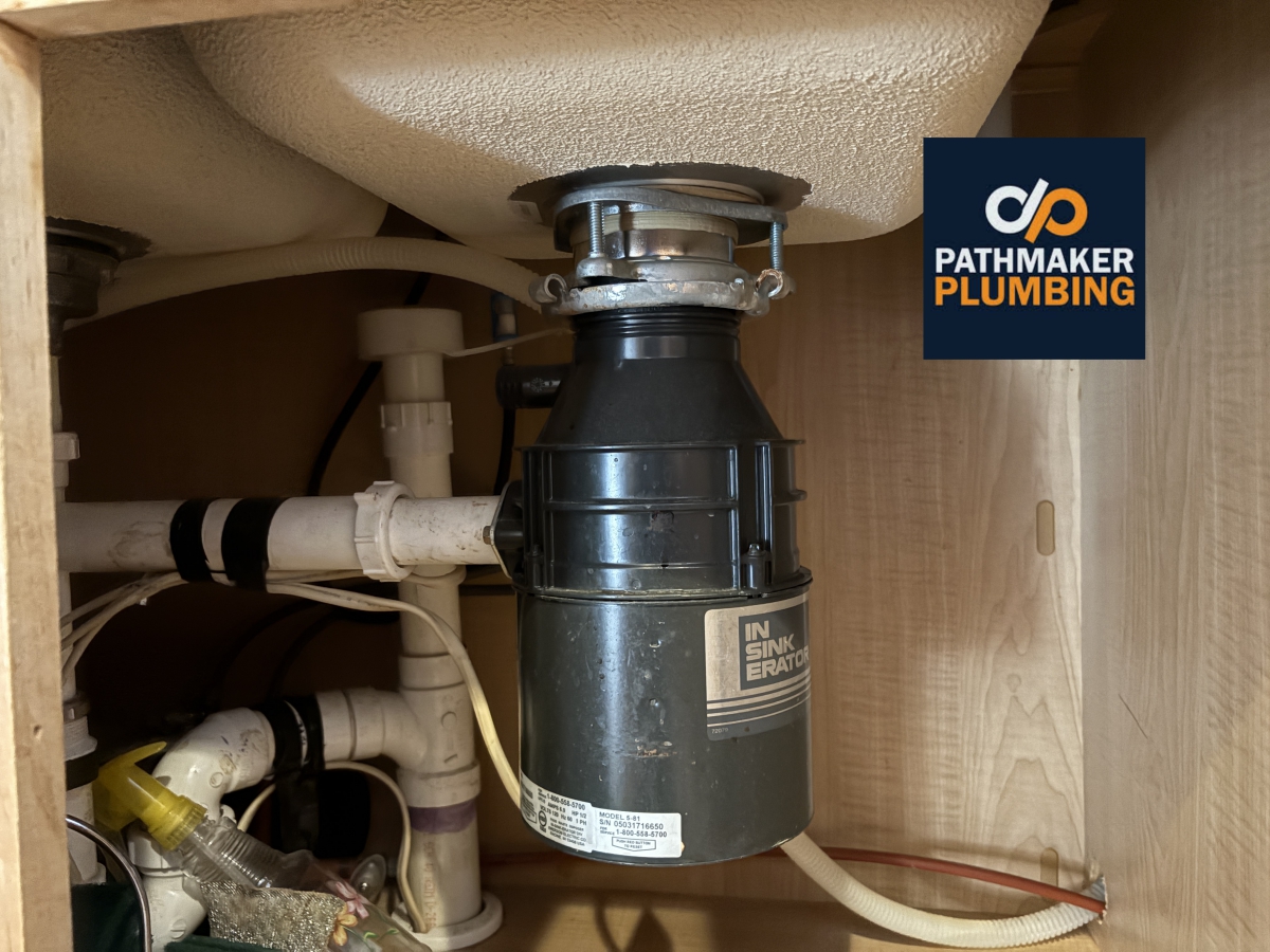 An in sink erator brand garbage disposal under a kitchen sink.