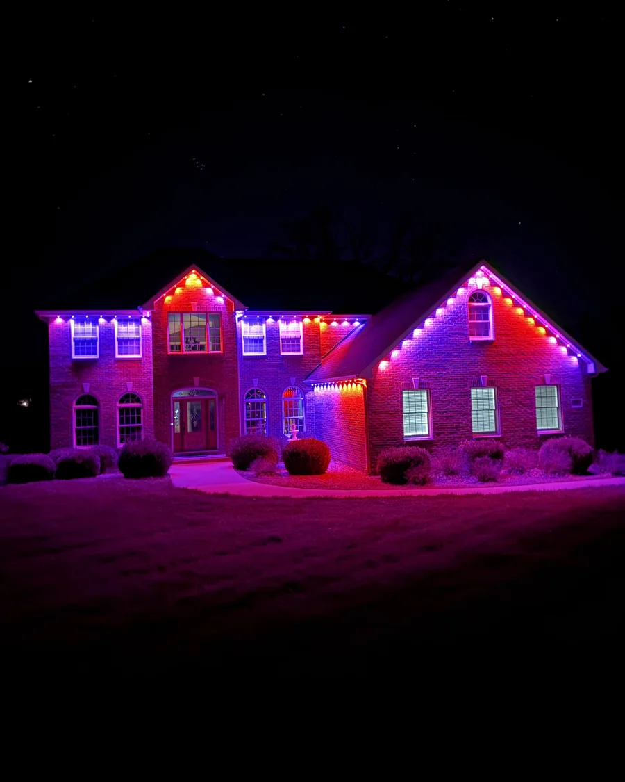 Brick home lit in purple and orange Halloween permanent lights