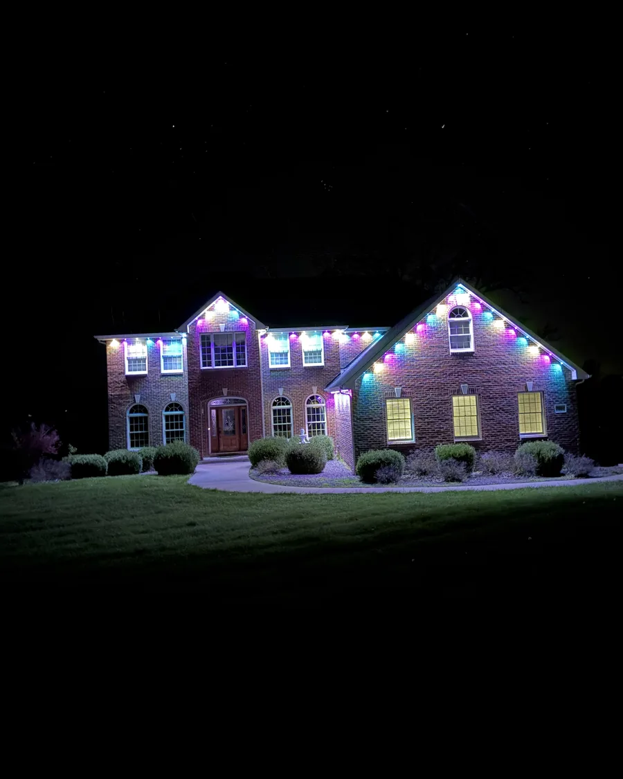 Brick home lit in pastel Easter colors with permanent lights