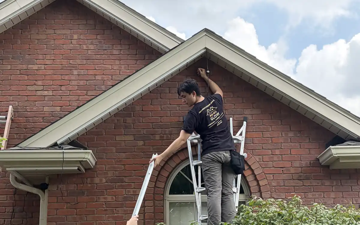 Two Mid Mo Glow installers mounting permanent lights on a brick home
