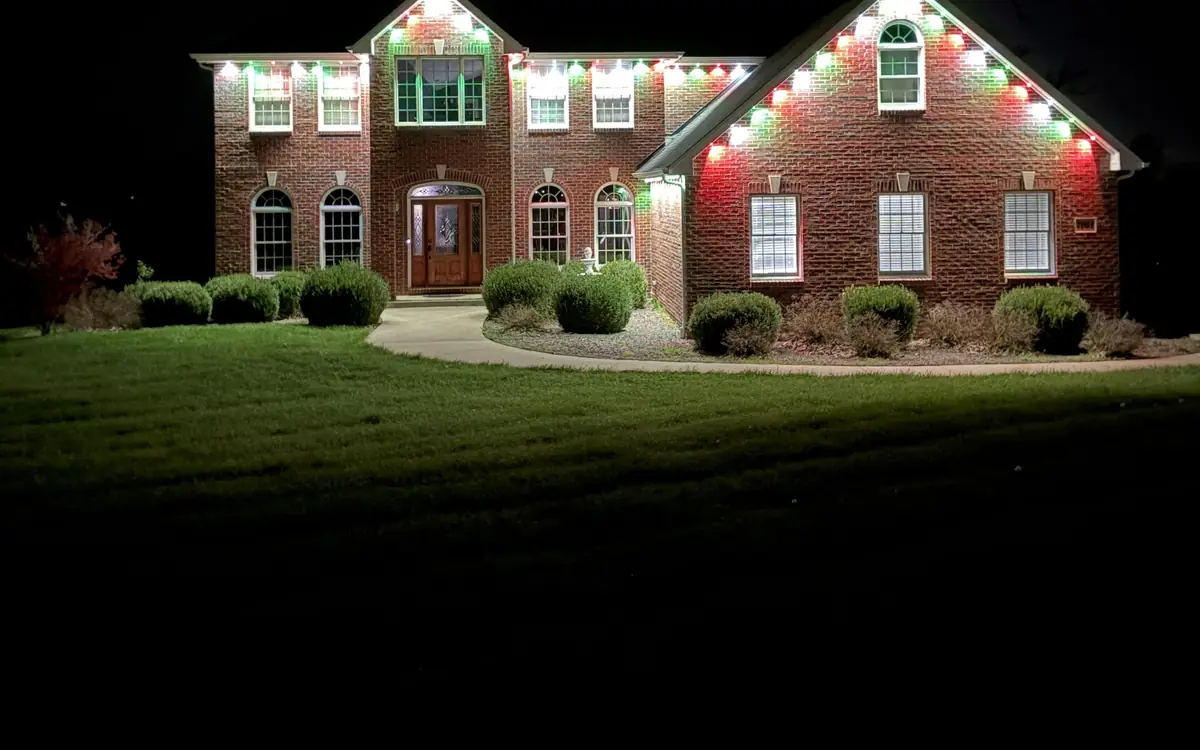 Brick home lit in red and green permanent holiday lights
