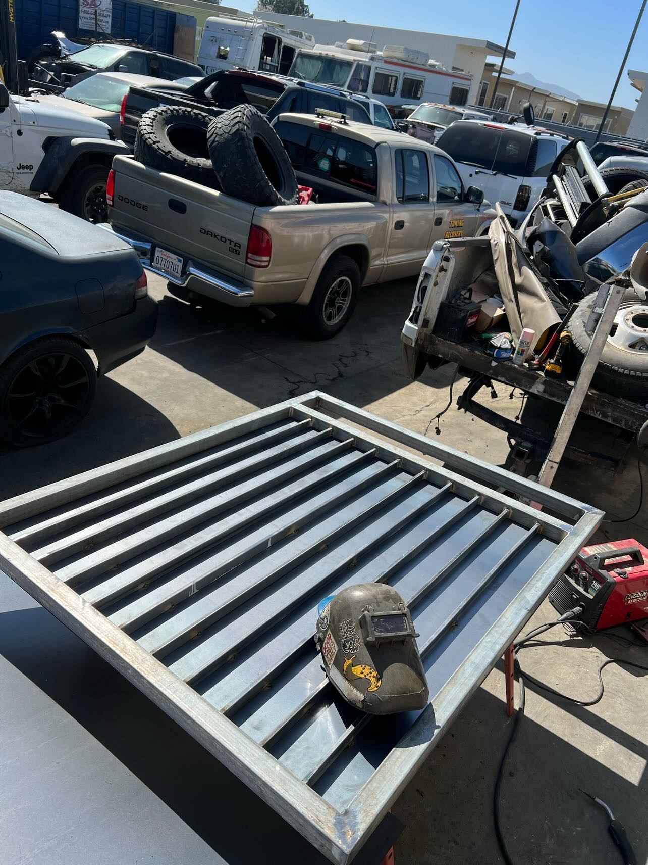 Professional welder in leather jacket and welding helmet fabricating a custom metal gate outdoors