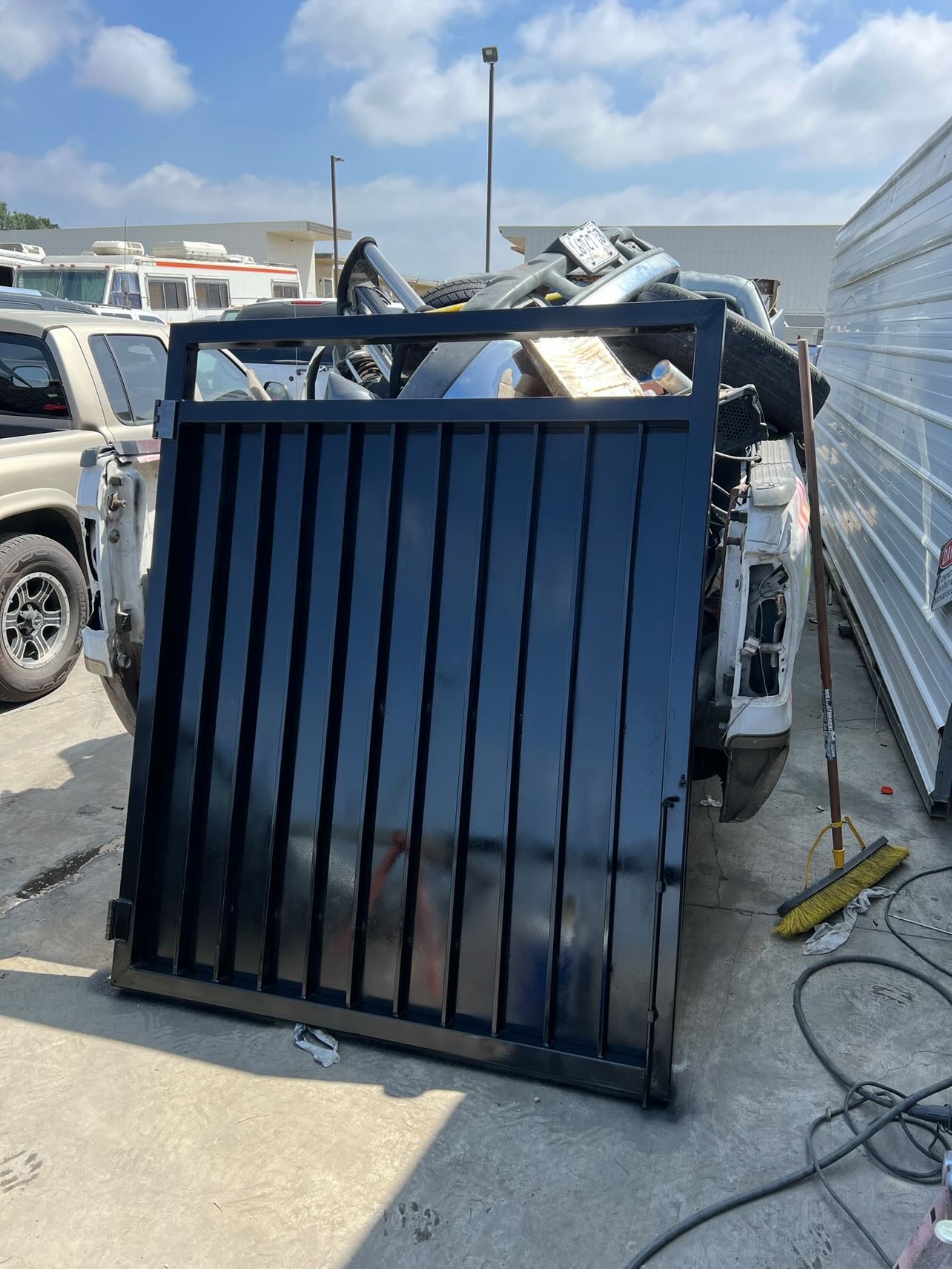 Custom fabricated black steel driveway gate with vertical pickets, powder coated finish, built by professional welders