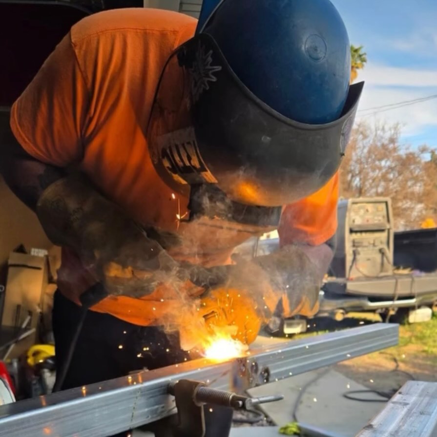 Skilled welder in helmet and safety shirt performing structural welding with sparks, professional welding services in Hemet and Riverside