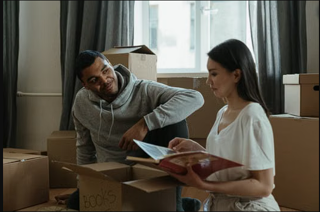 Military couple packing for a move while reviewing paperwork for a VA loan in another state. Military couple packing for a move while reviewing paperwork for a VA loan in another state.