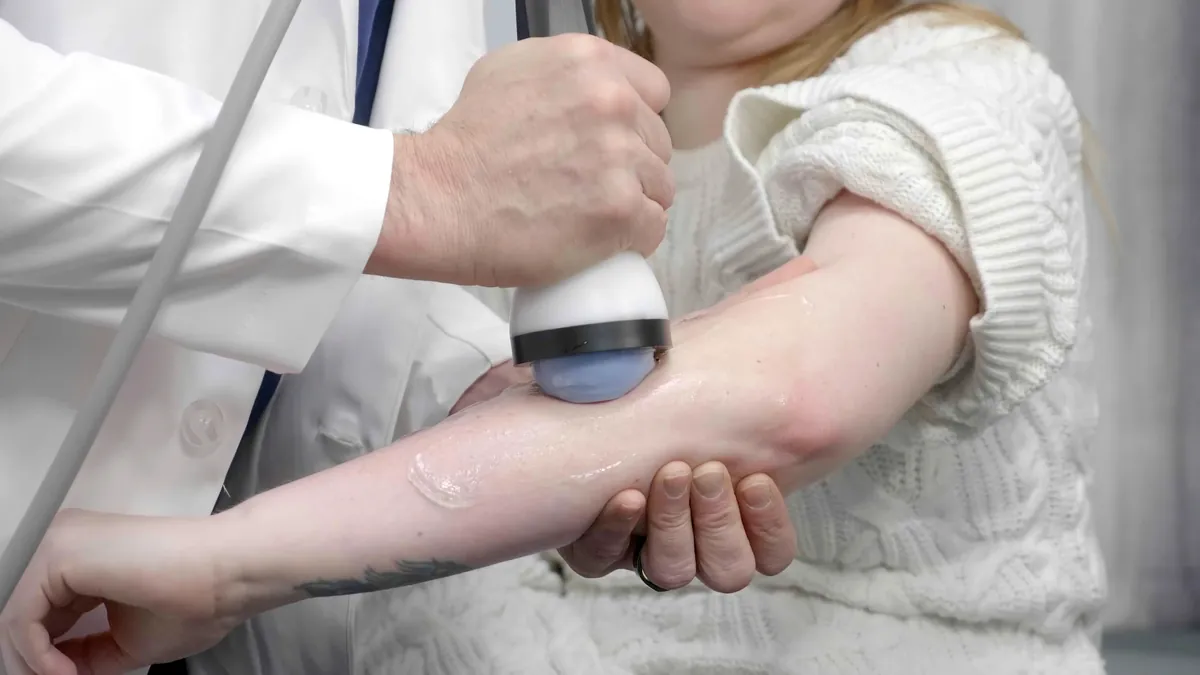 Clinician steadying a patient's forearm while treating near the elbow with StemWave