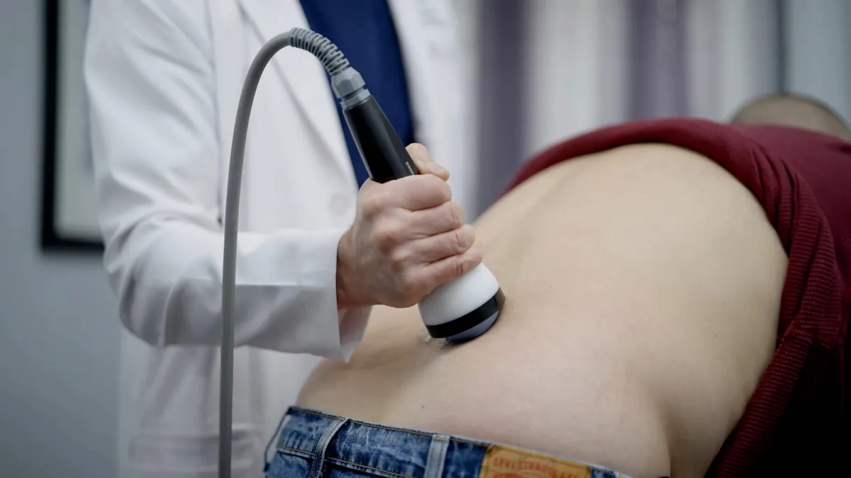 StemWave applicator on the lower back while the patient stands leaning forward