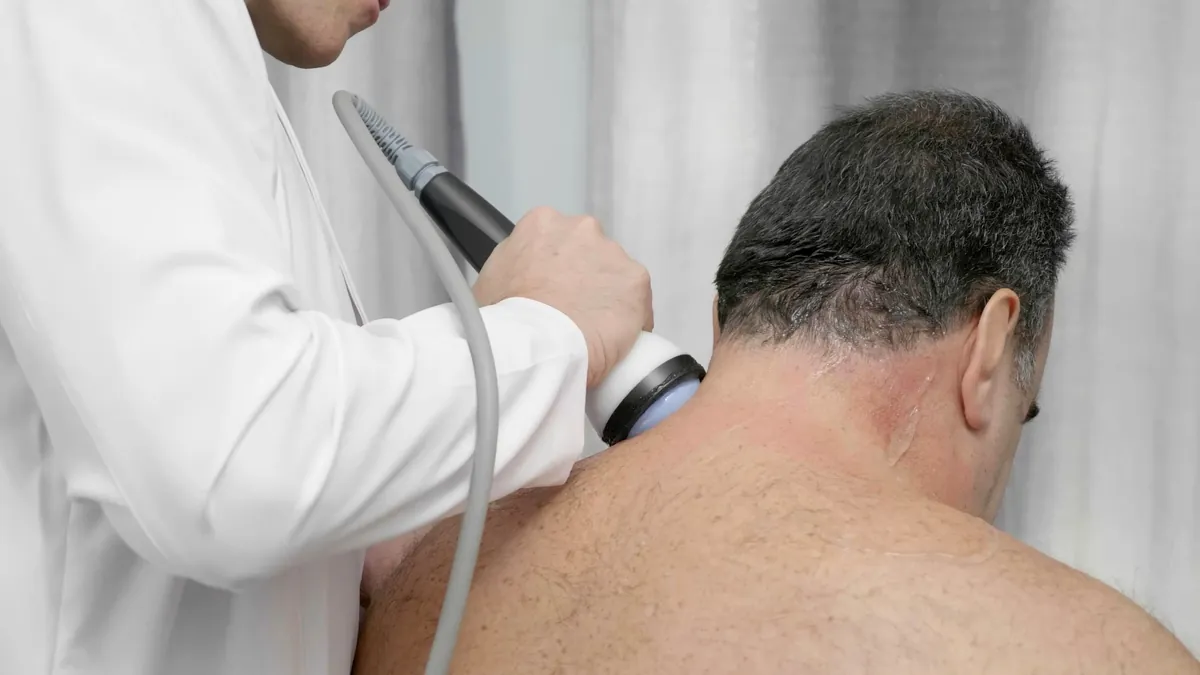 Clinician treating the base of a man's neck and upper back with StemWave