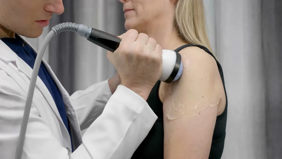 Clinician treating the front of a woman's shoulder with the StemWave applicator