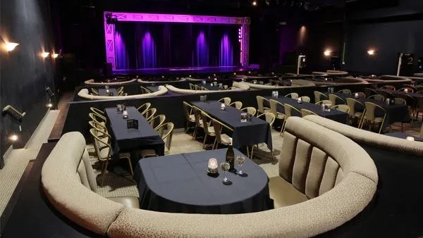 Greg Frewin Theatrical Centre interior showing stage, tiered booth seating, and cabaret tables