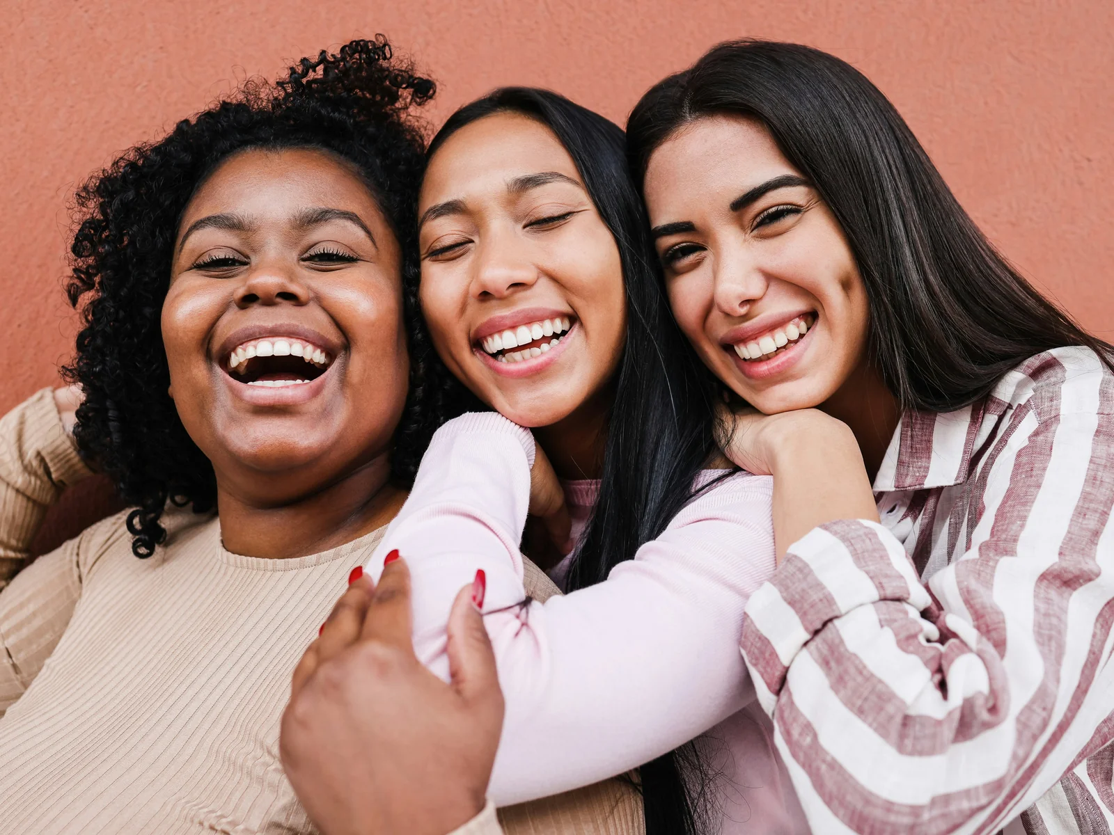 Three women embracing and laughing together