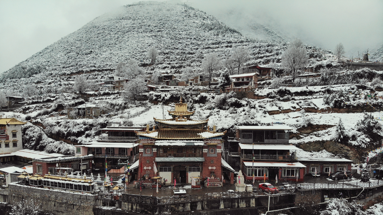Snow-covered Tibetan monastery beneath a mountain