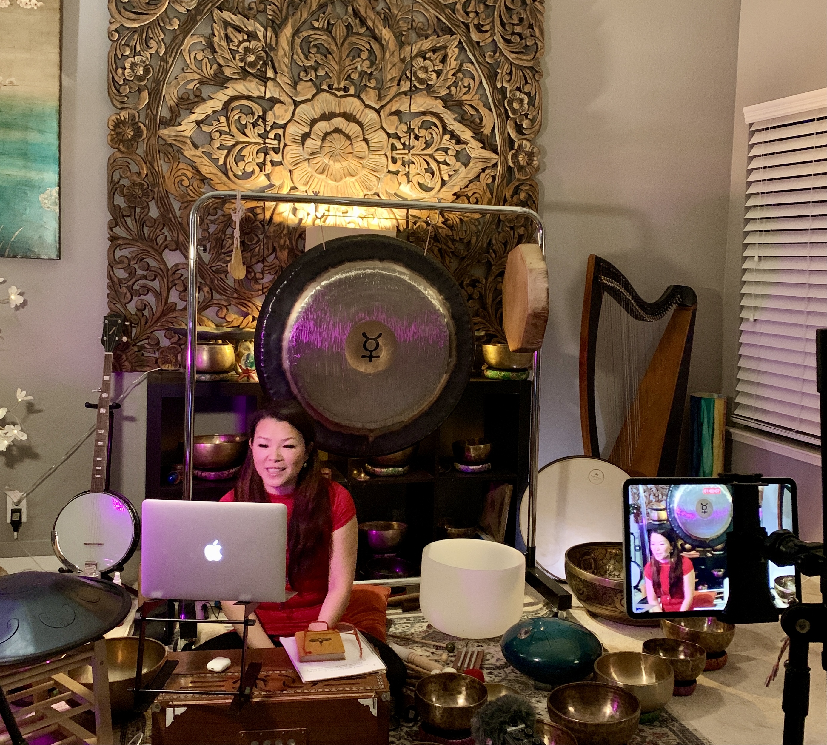 Riya Wang leading a private online Tibetan Singing Bowl session with her laptop, bowls, and gong