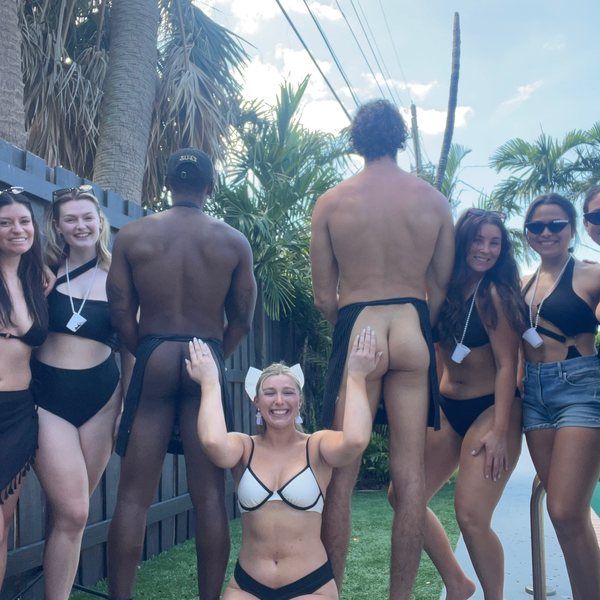 Two Cheeky Butlers in signature aprons with a group at a pool party