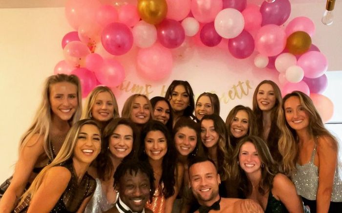A bachelorette group with their Cheeky Butler in front of a balloon arch