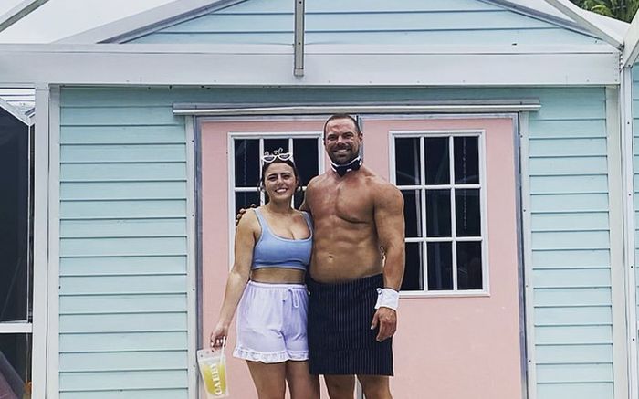 A baby shower guest with a butler outside a pastel house