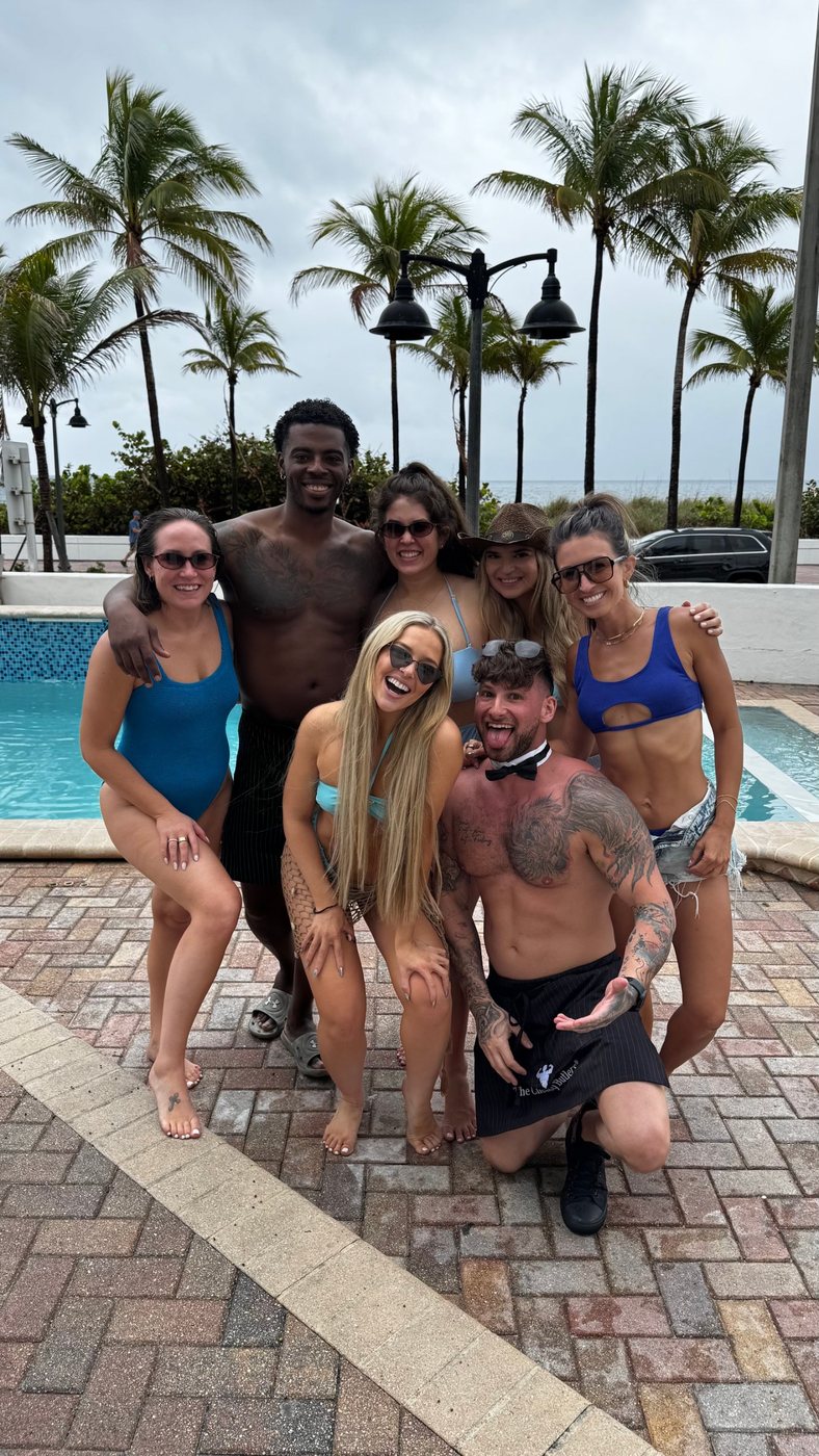 A bachelorette group poolside with two Cheeky Butlers on a beachfront pool deck