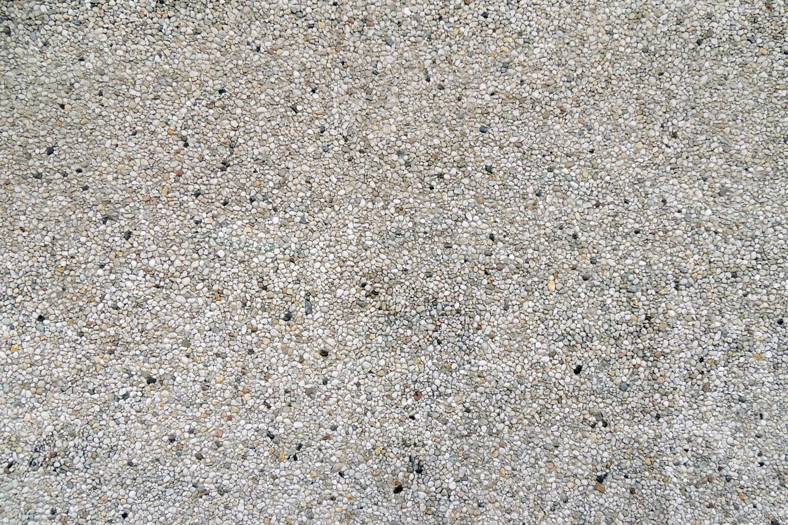 Gros plan sur la texture d'un béton désactivé gravillonné, revêtement esthétique pour des allées carrossables et terrasses antidérapantes.