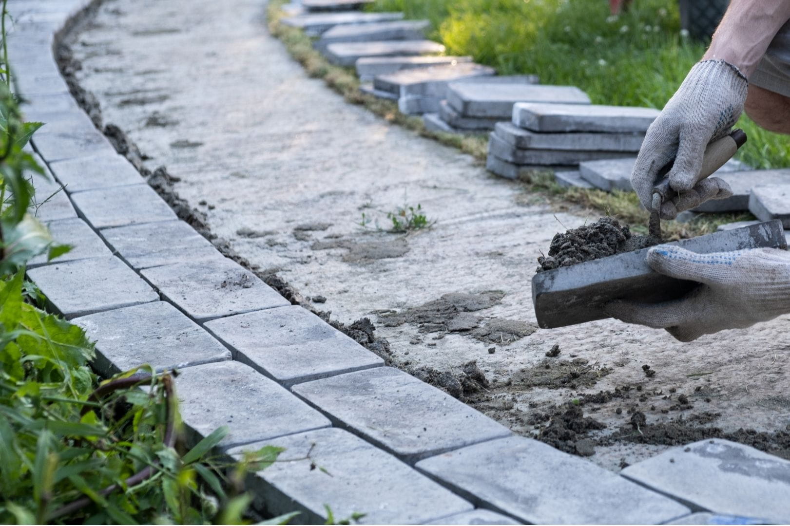Artisan paysagiste d'Armen Batipro réalisant la pose soignée de pavés sur lit de sable pour la création d'une allée.