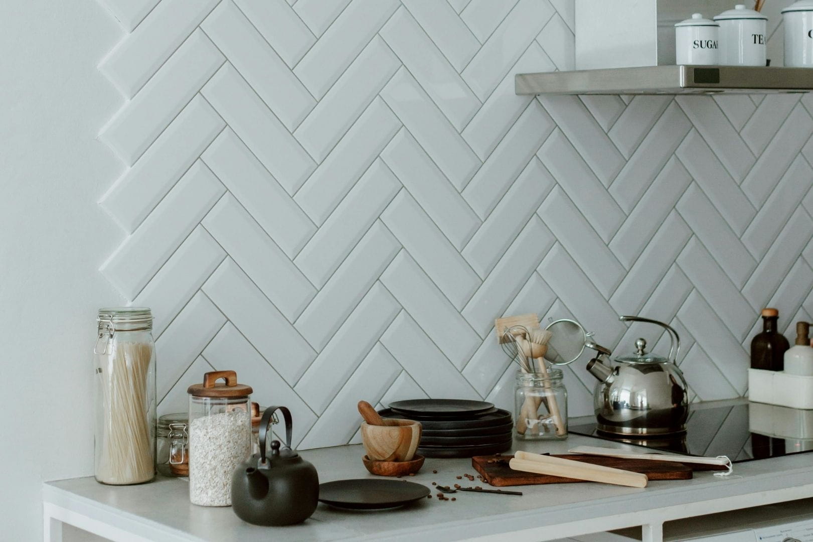 Pose de faïence blanche en chevrons sur un mur de cuisine pour une décoration moderne et lumineuse.