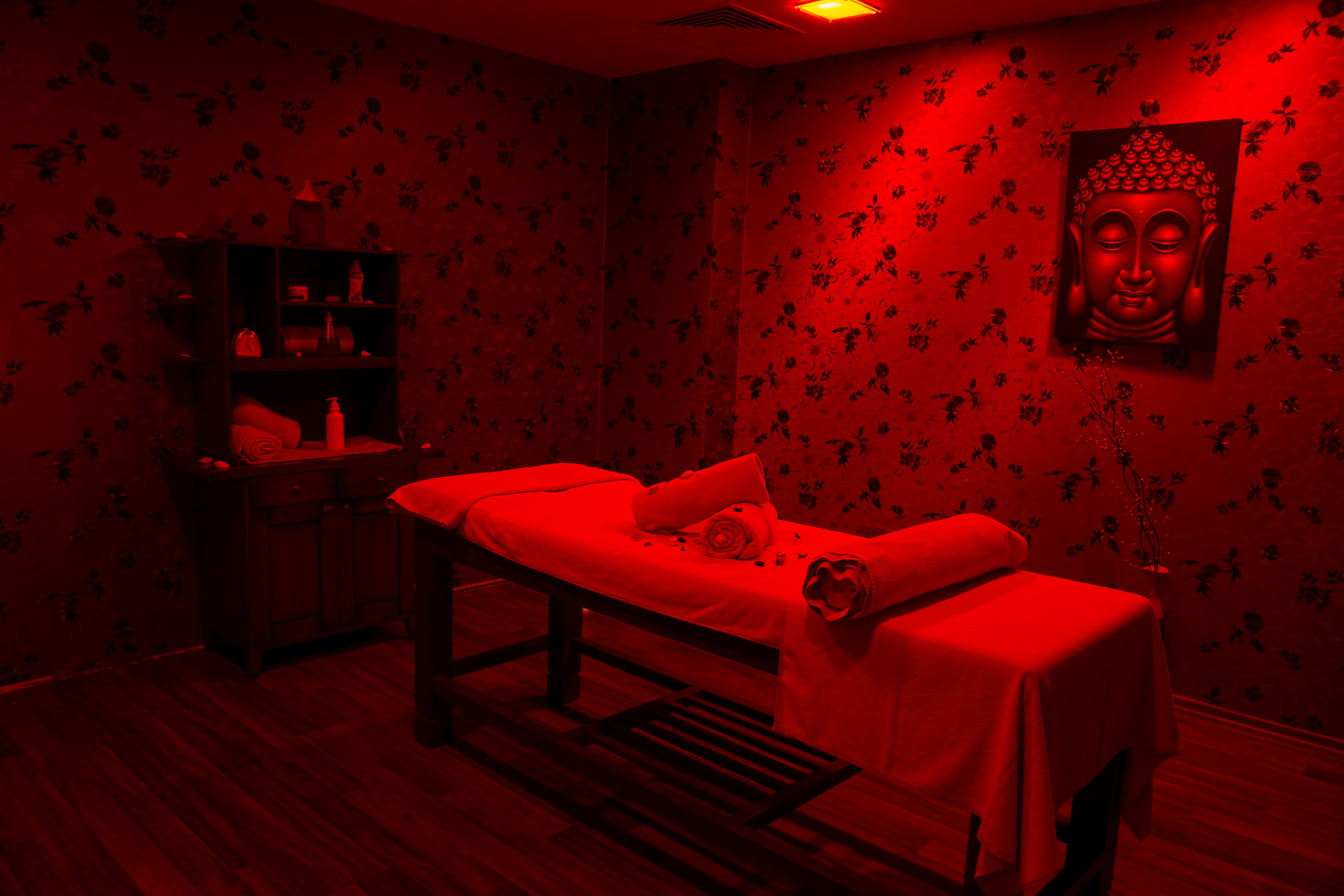 Massage Table in a Room with Red Light and Buddha Picture on the Wall