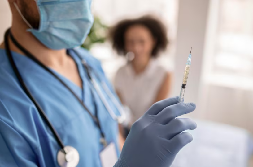 Doctor holding a syringe with for IV therapy next to a woman patient
