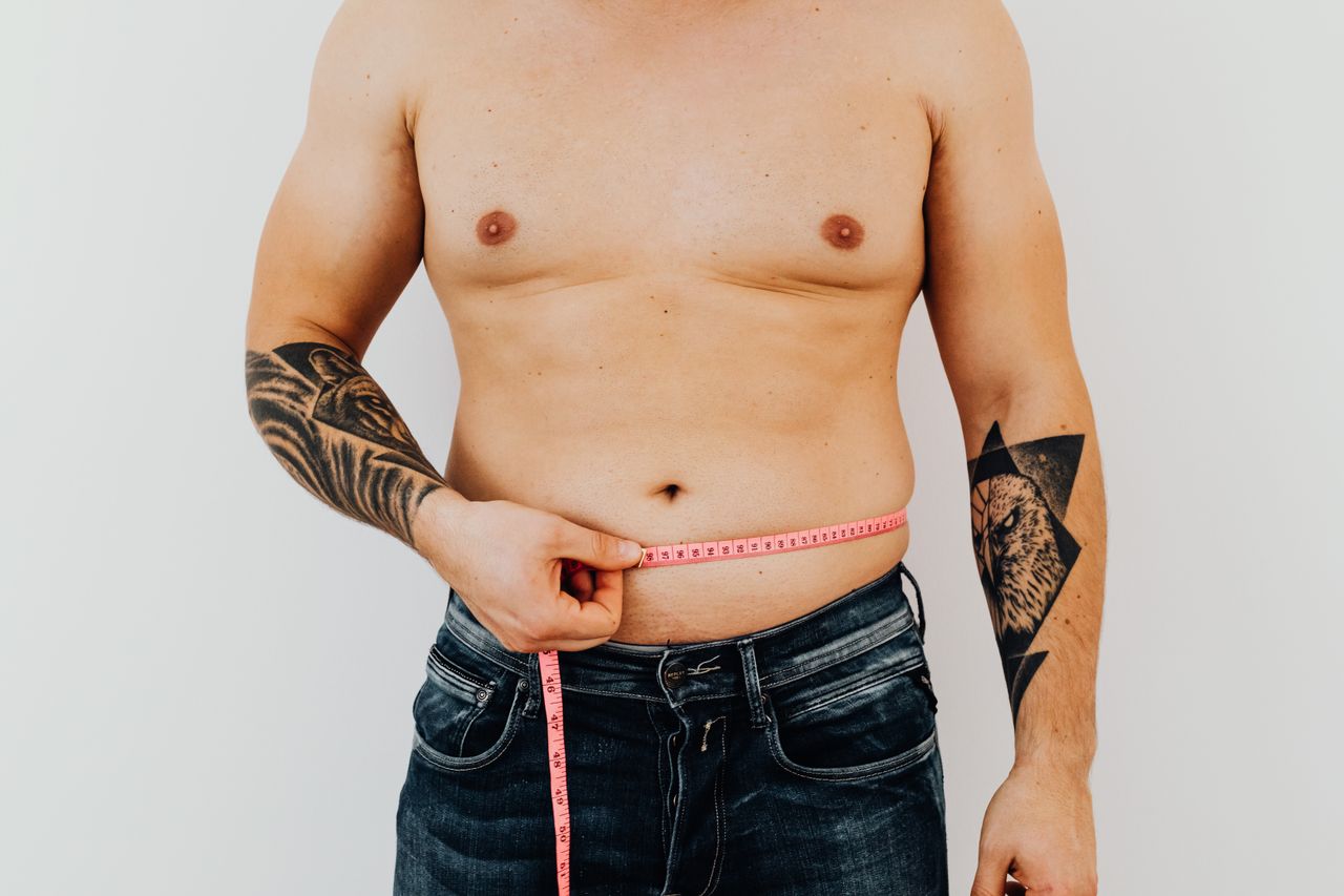 Man holding a measuring tape across his body Man holding a measuring tape across his body