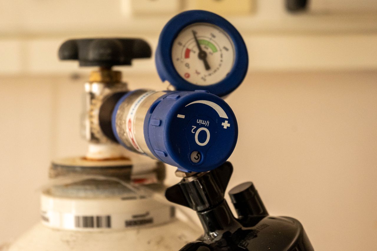 Detailed view of an oxygen tank with a pressure gauge, showcasing medical equipment usage. Detailed view of an oxygen tank with a pressure gauge, showcasing medical equipment usage.