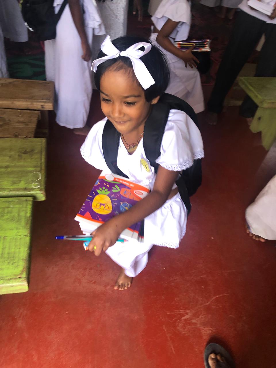 Young girl receiving school supplies after Cyclone Ditwa relief program in Ududumbara Sri Lanka