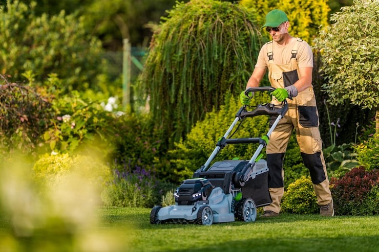 Professional landscaping team member from SGJ Landscaping mowing a vibrant residential garden in Honesdale, PA.