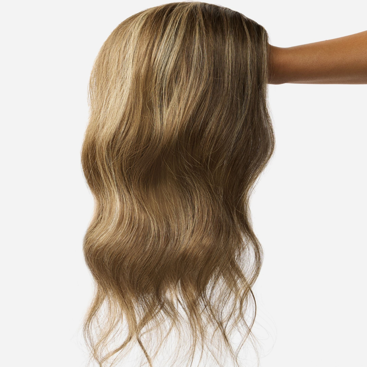 A wavy, dimensional bronde human hair wig held up against a light background
